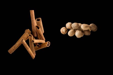Freeze motion of flying group of Cinnamon stick and whole nutmeg seed isolated on black background.