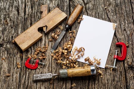 Blank business card on wooden table with carpenter tools and sawdust top view.の写真素材