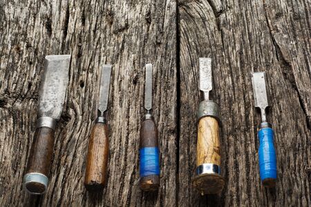 Carpenter tools composition. Old carpenter chisels laying on rustic wooden table upper view.