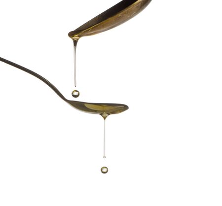 Pouring oil splash on spoon. Isolated on white background.の写真素材