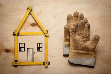 House concept with yellow meter and working gloves on wooden backgroundの写真素材