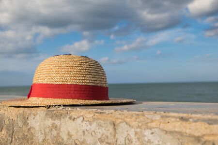 Strawhat with red ribbon near seaの写真素材