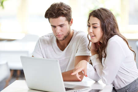 Two young business people in casual wear looking at the laptop. Business people Having Meeting Around Table In Modern Office.の写真素材