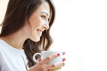 Coffee makes her day. Young handsome woman drinking coffee and looking away, isolated on white. Openspace, co-working, time cafeの写真素材