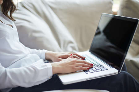 Close-up of hands typing on laptop keyboard in the home officeの写真素材