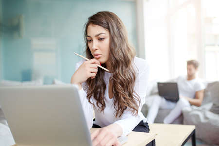 Businesswoman at workplace. Front portrait of beautiful woman in modern business office looking to laptop. Young business woman working in office. Green office. Life style.の写真素材