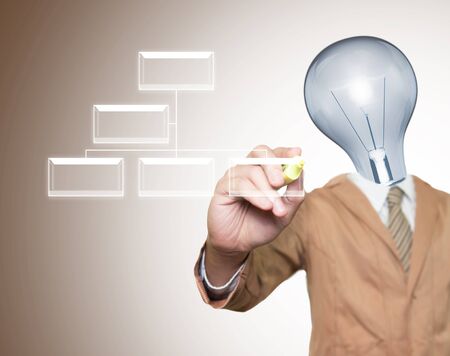 Young businessman with lamp-head and marker writting light box on screenの写真素材