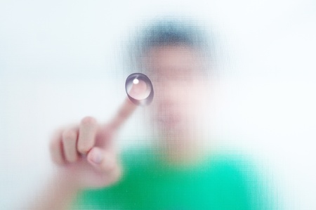 man finger pressing a touchscreen button with water dropの写真素材