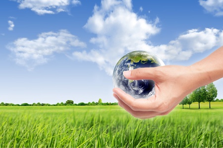 Hand with earth globe on green grass landscape background, ecology conceptの写真素材