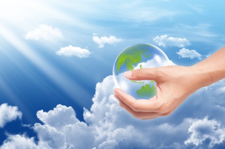 Hand with earth globe on blue sky background, ecology conceptの写真素材