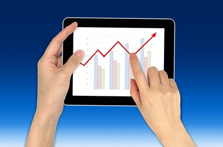 Hand with graph and touchscreen device showing business and investment conceptの写真素材