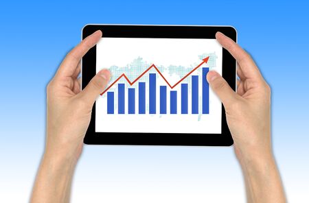 Hand with graph and touchscreen device showing business and investment conceptの写真素材