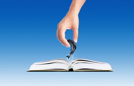 3D open green grass book with jumping fish imagination and conceptual ideaの写真素材