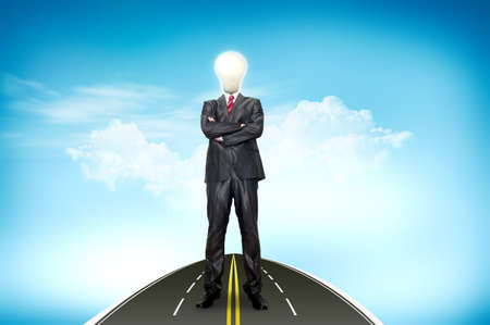 A business man bulb standing over road and blue sky the backgroundの写真素材