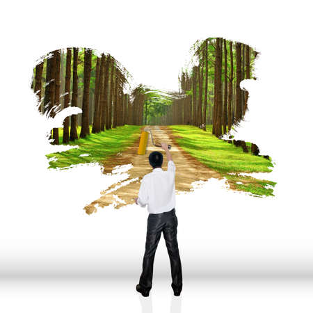 Young business man with paint brush and wall with natural landscapeの写真素材