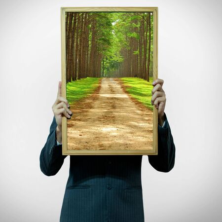 Business man holding tree landscape inside board on the backgroundの写真素材