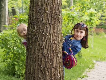 Two girls peeking from a treeの写真素材