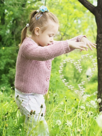 Girl enchant dandelion in shape of heartの写真素材
