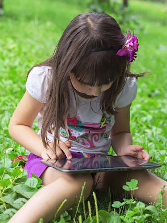 Girl with tablet pc in the meadowの写真素材