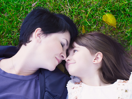 Mother and daughter lie on the grassの写真素材