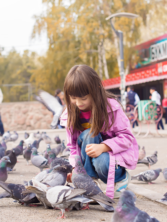 Small caucasian girl feeding pigeonsの写真素材