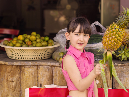 Little caucasian girl holding pineappleの写真素材