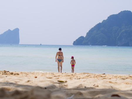 Mother and her little daughter on tropical white sand beach on islandの写真素材
