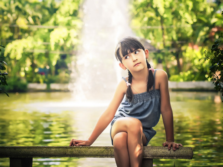 Portrait of little caucasian girl sitting on the bench outdoorsの写真素材