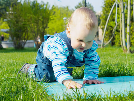 Portrait of nice caucasian baby boy playing at summer park outdoorsの写真素材
