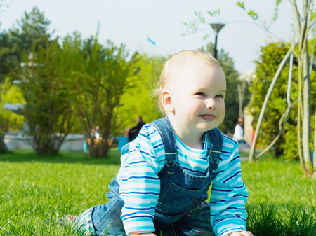 Portrait of nice caucasian baby boy playing at summer park outdoorsの写真素材