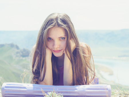 Portrait of young caucasian beautiful sport women lying on travel mat  in summer nature on the background of riverの写真素材