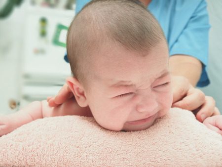 Baby massage doctor massage small caucasian crying baby boy backの写真素材