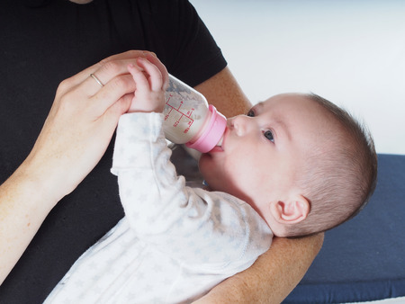 Caucasian baby boy four months drinking milk from the bottle at homeの写真素材