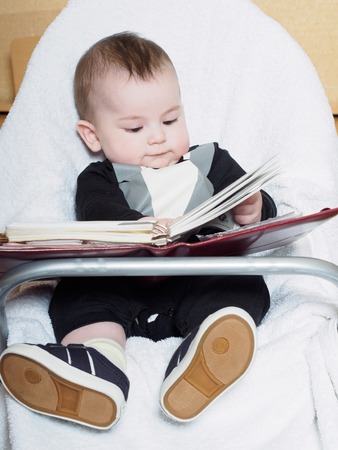 Small caucasian baby sitting in chear with notepadの写真素材