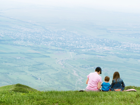Portrait of family mother, brother and sister together sitting in nature outdoorの写真素材