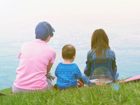 Portrait of family mother, brother and sister together sitting in nature outdoorの写真素材