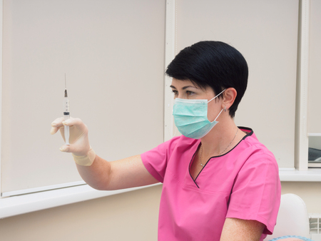 Medical doctor with syringe preparing to make injection to patientの写真素材