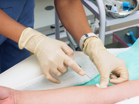 Doctor drawing blood from female patient's arm in examination roomの写真素材