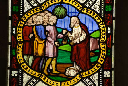 Victorian stained glass window, over 100 years old, showing a money lender measuring out a sack of...