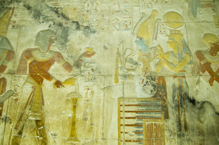 Ancient Egyptian bas relief carving showing the Pharaoh Seti I making an offering of incense to the god of the underworld Osiris with his wife, the goddess Isis standing behind    Wall of the temple to Osiris at Abydos, el Balyana, Egypt のeditorial素材