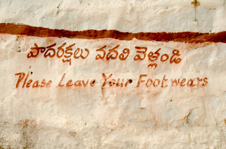 Hand painted sign in English and Telugu asking visitors to an historic Hindu temple to remove their shoes   Golcanda Fort, Hyderabad, India のeditorial素材
