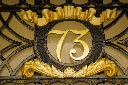 Ornate metal sign for number 73 on the exterior of a Georgian townhouse in central London  On public display over 150 years and viewed from pavement のeditorial素材