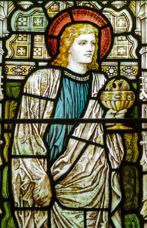 Victorian stained glass window showing the Apostle St John the Evangelist holding a chalice containing a winged serpent Historic window on public display over 100 years Victorian stained glass window showing the Apostle St John the Evangelist holding a chalice containing a winged serpent Historic window on public display over 100 years