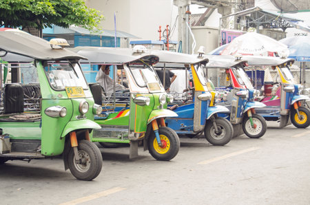 BANGKOK, THAILAND - OCTOBER 27 2013  A row of tuk tuk motorcycle taxis at the side of a road in the...