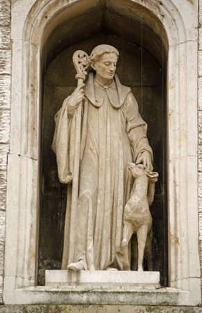 Statue of Saint Giles with a hind  deer  on the exterior of St Giles Cripplegate church in the Barbican, City of London   Historic statue viewed from public pavement の写真素材