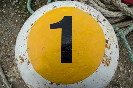 A bollard for mooring ships with a large number one painted on it   Southampton docks 