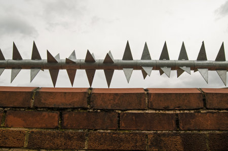 Sharp rotating metal spikes protecting the top of a wall in East London.のeditorial素材