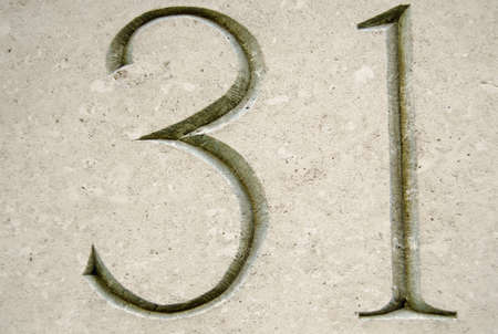 Number thirty one carved into stone on the outside of a building in the City of London.  Viewed from a public pavementの写真素材