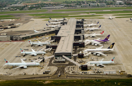 LONDON, UK - MAY 30, 2016: Aerial view of aeroplanes standing at Terminal 2 of London Heathrow Airport on a cloudy day in May. Airlines using this terminal include Air Canada, Singapore Airlines and United Airlines.のeditorial素材