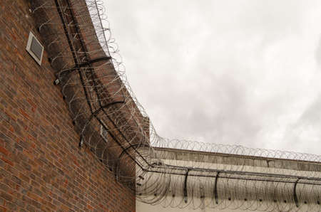 Looking up at the tall wall surrounding Reading Prison with razor wire coiled around the top to deter escape.  Berkshire.  The prison once had playwright Oscar Wilde as an inmate..の写真素材